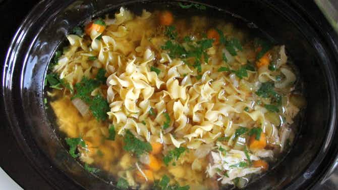 A crockpot soup with noodles, carrots and broth