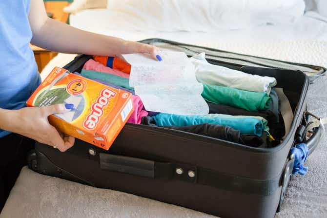 woman placing dryer sheets in luggage