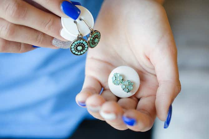 A woman holding up earrings that are attached to large buttons