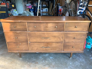 A scuffed up vintage dresser in a garage.
