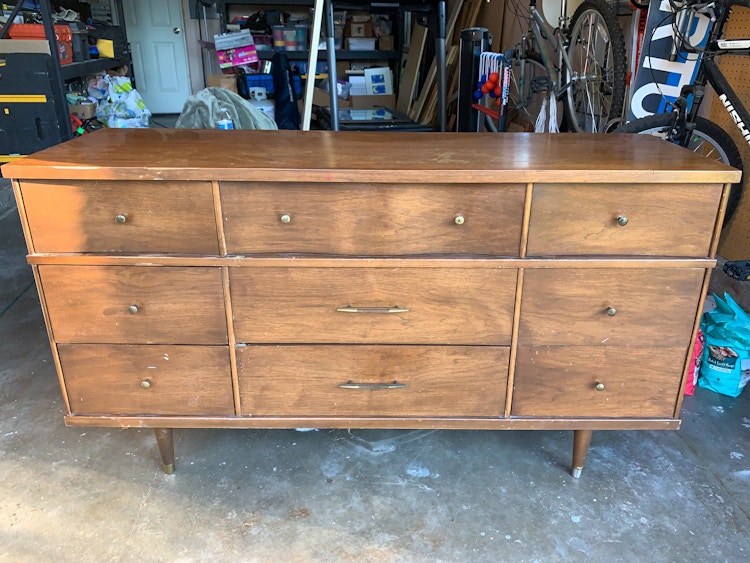 A scuffed up vintage dresser in a garage.