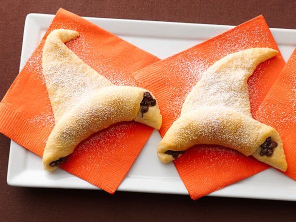 Some chocolate crescent witch hats sitting on a plate with orange napkins