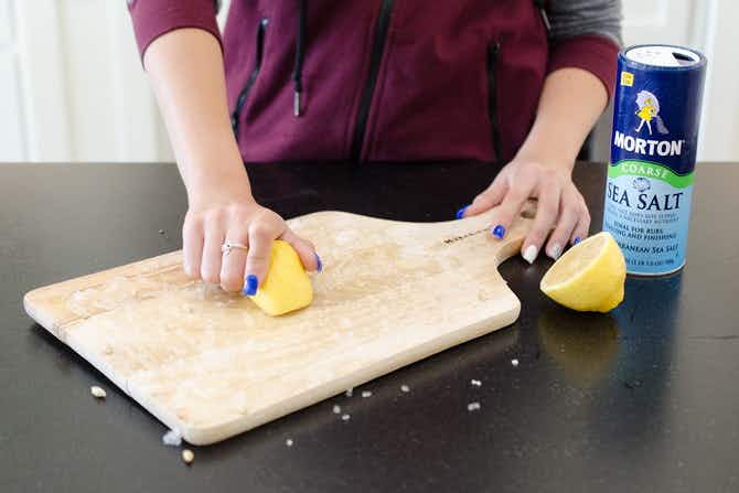 someone scrubbing wood cutting boards with lemon and salt.