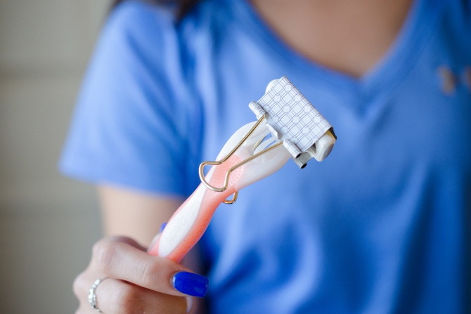 Someone holding a razor with a binder clip covering the blade