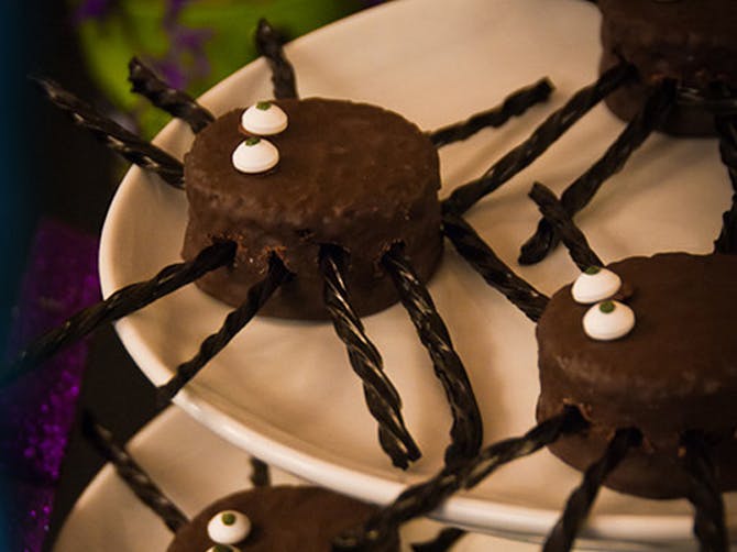 Chocolate wagon wheel deserts with edible eye candies on top and eight pieces of licorice sticking out the sides to make them look like spiders.
