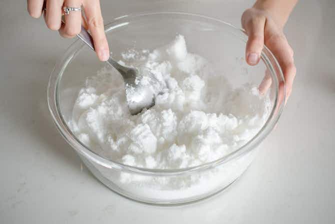 a person using a spoon to combined ingredients in a bowl 