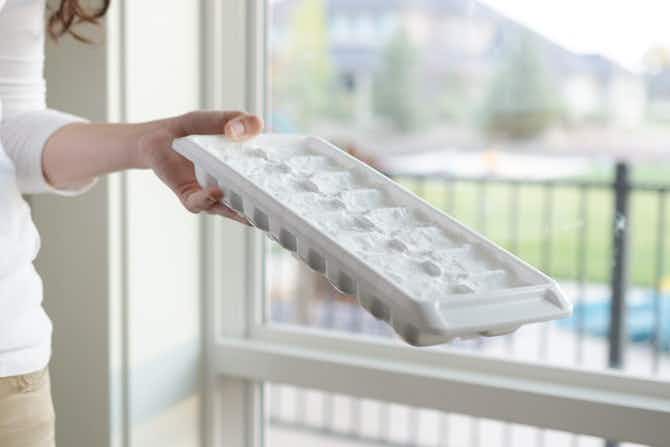 a person putting an ice cube tray with detergent dry in a sunny window
