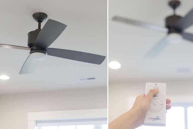 A ceiling fan, and a person's hand pointing a remote at the ceiling fan to change the direction of the fan.