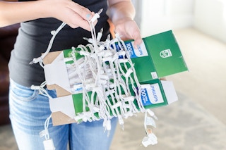 A person wrapping a strand of light around a piece of cardboard.