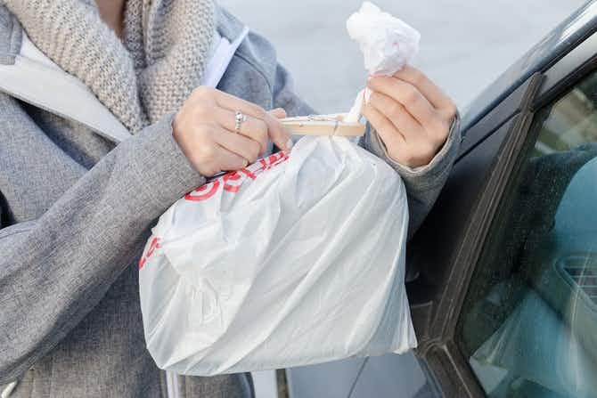 A person covering a side mirror with a plastic bag and a clothes pin