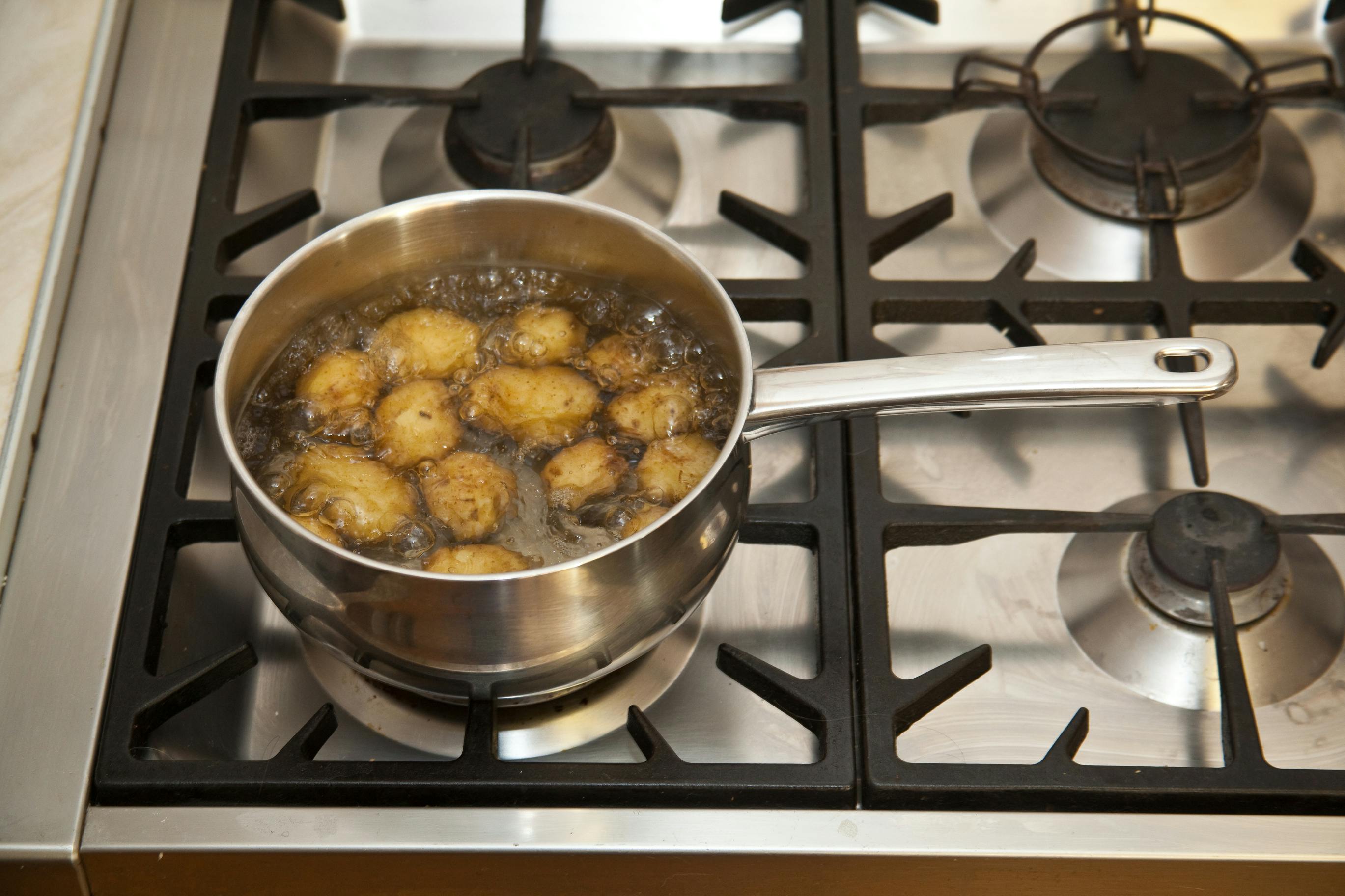 A pot of potatoes boiling on a stove.
