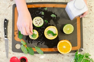 Someone making a homemade air freshener with citrus rinds, salt and mint