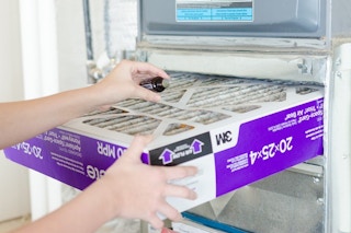 Woman adding drops of essential oil to an air conditioner filter