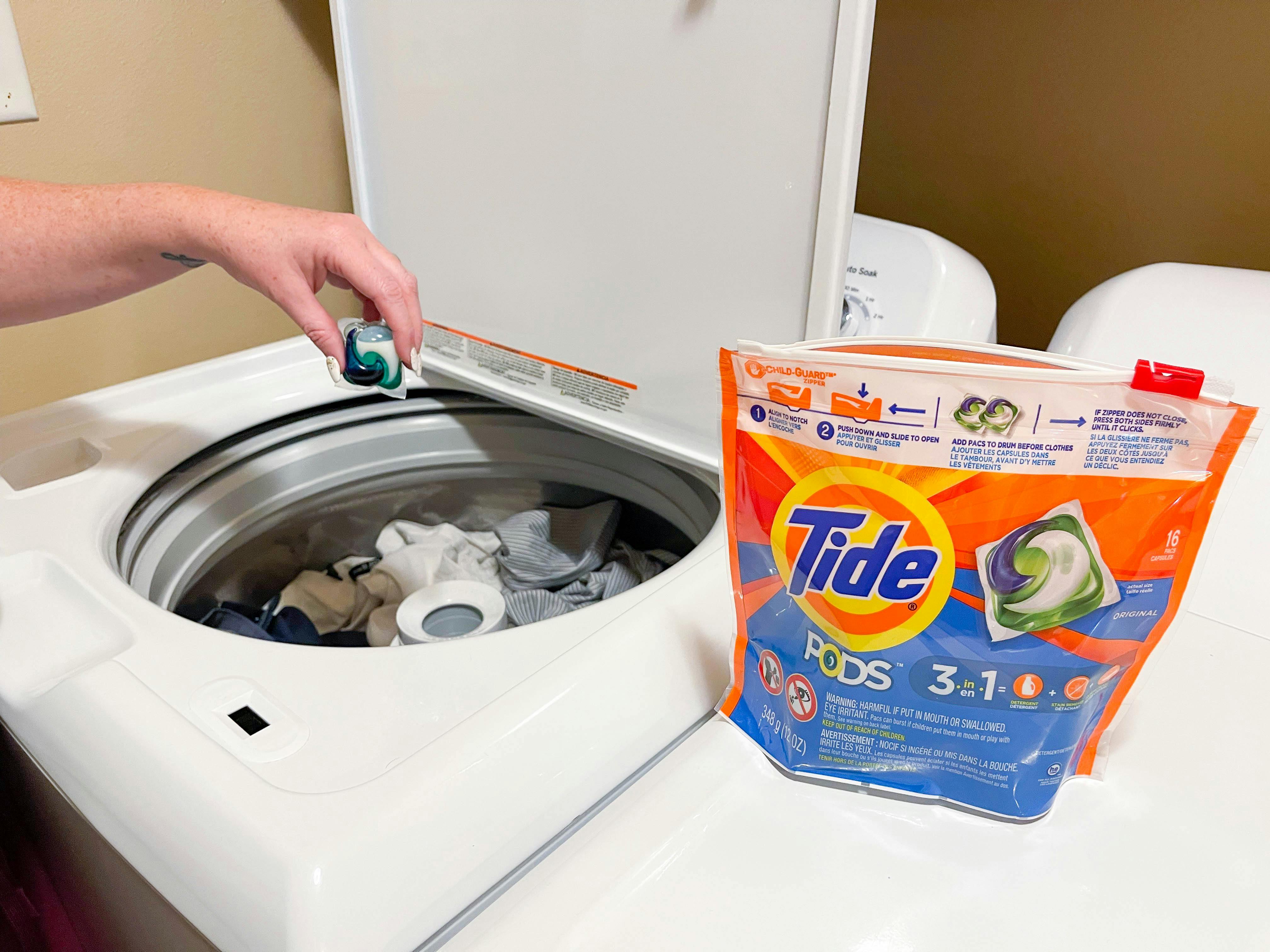 putting a tide pod in washer filled with clothes