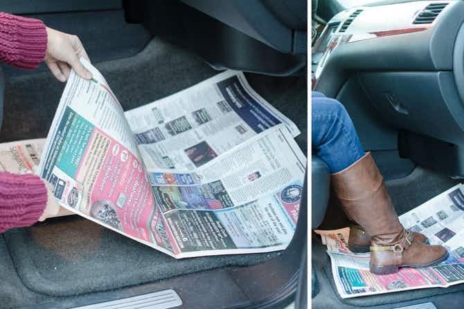 A person laying newspaper in the floorboards of a car.