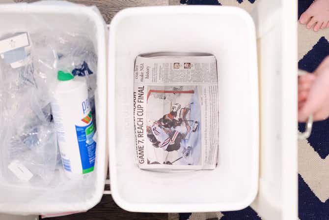 A garbage can with newspaper in the bottom.