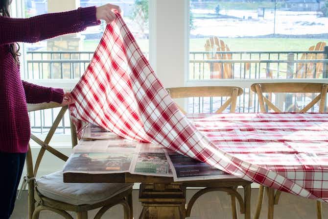 Protect a wood table from spills by setting down newspaper underneath a tablecloth.