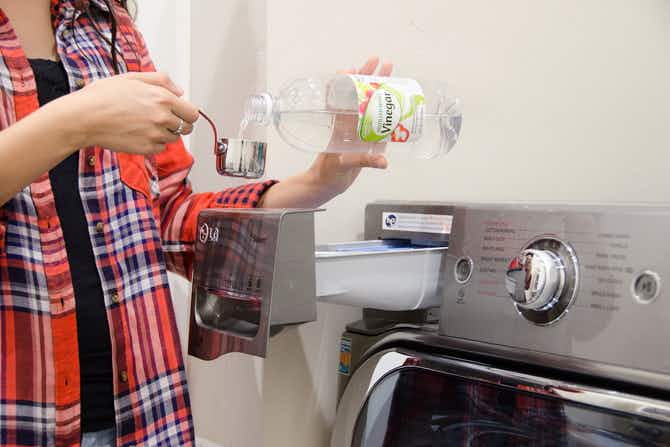 woman pouring white vinegar into measuring cup to sanitize laundry