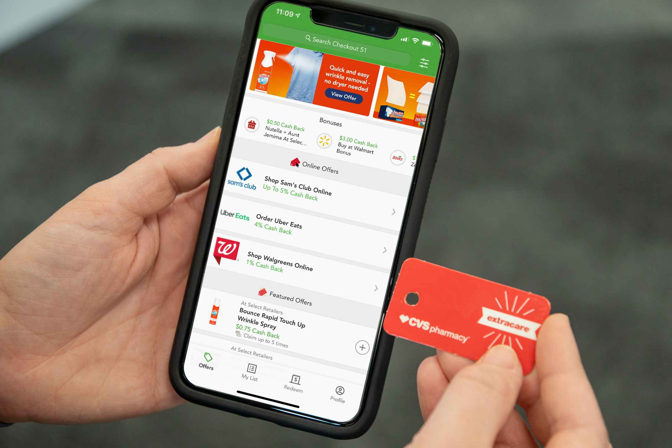 A person holding a cell phone with the Checkout 51 app on one and and a CVS loyalty card in the other hand.