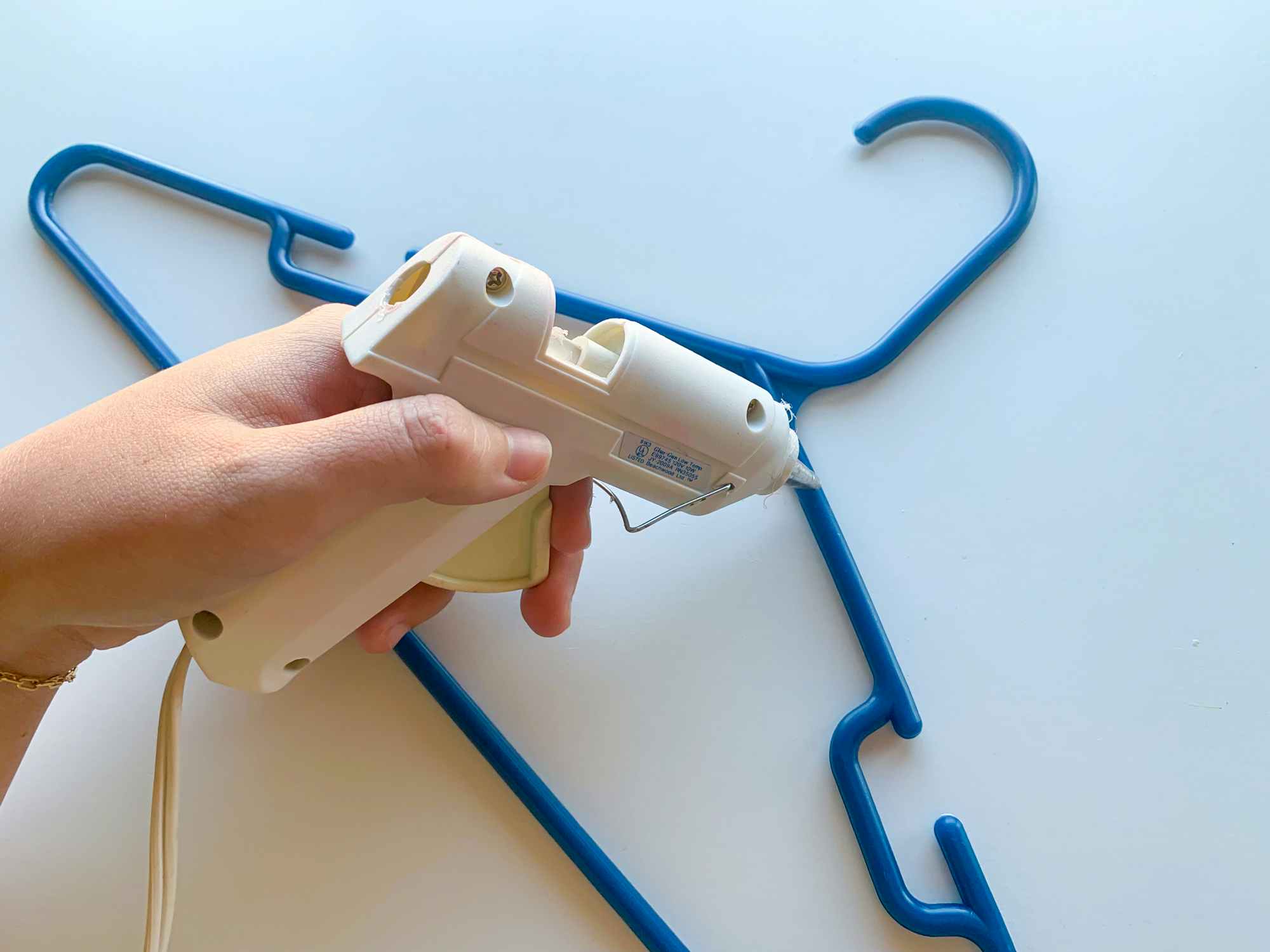 a person putting hot glue onto a hanger