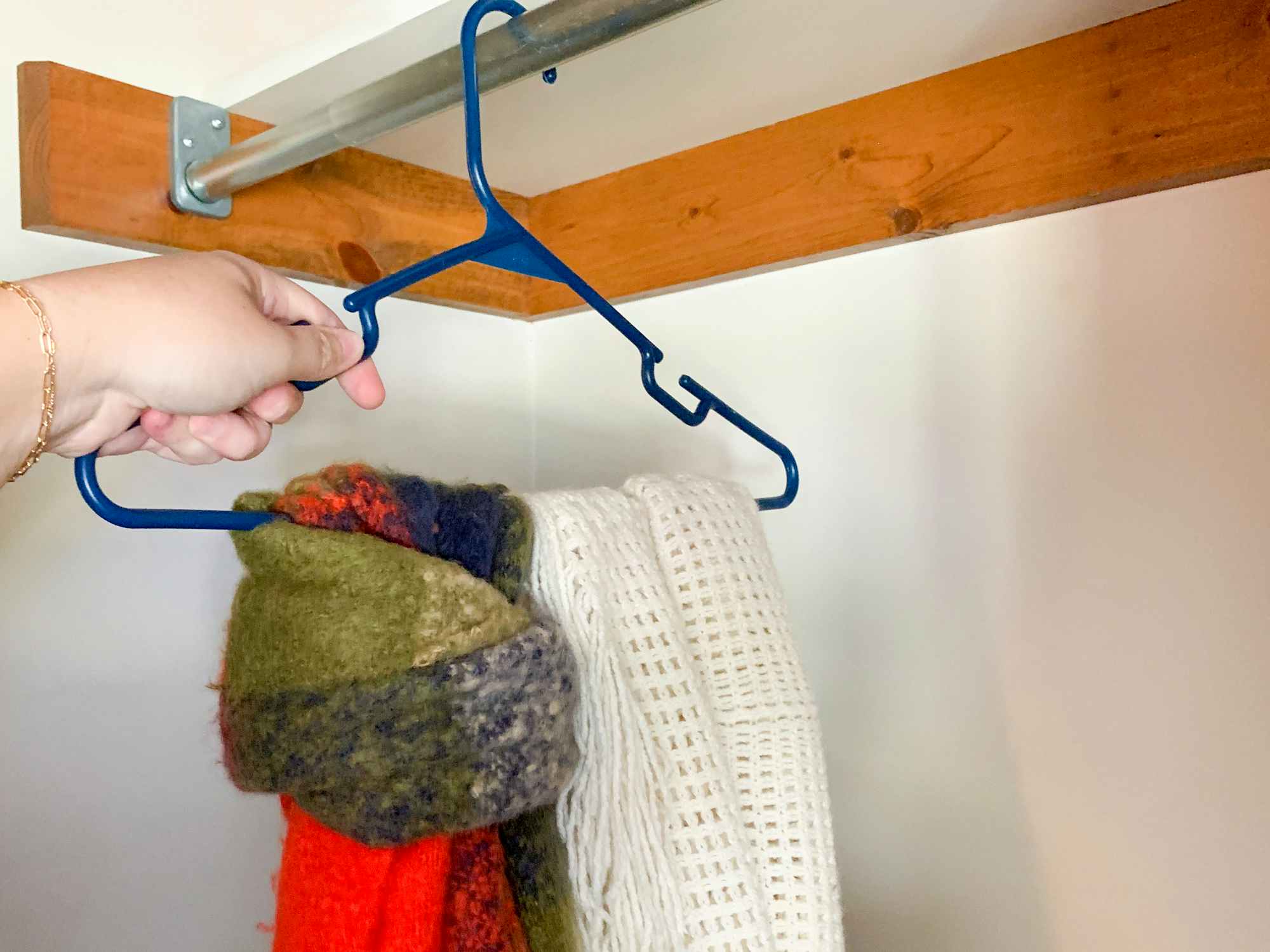 a person hanging scarves in their closet with a clothes hanger