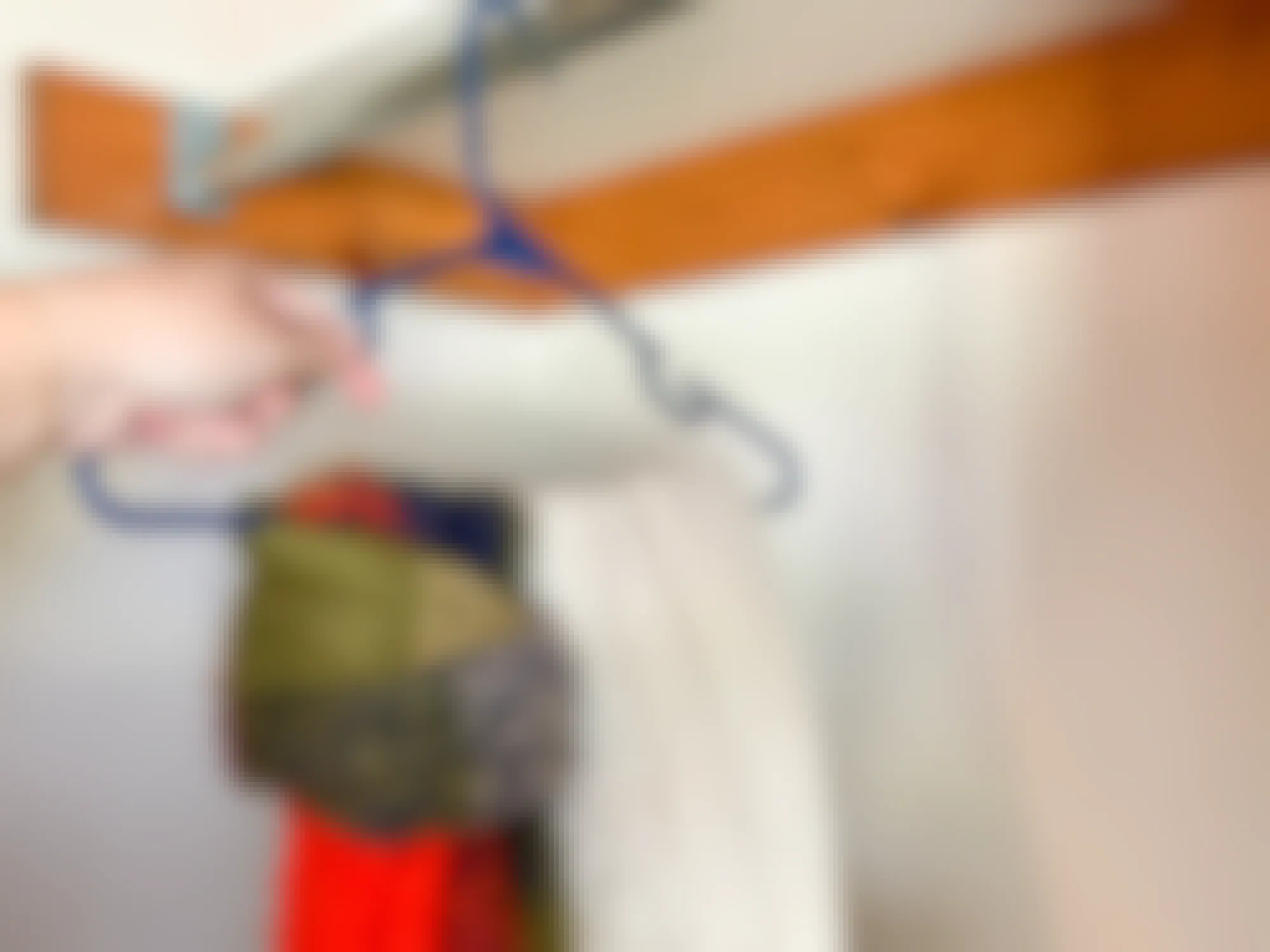 a person hanging scarves in their closet with a clothes hanger