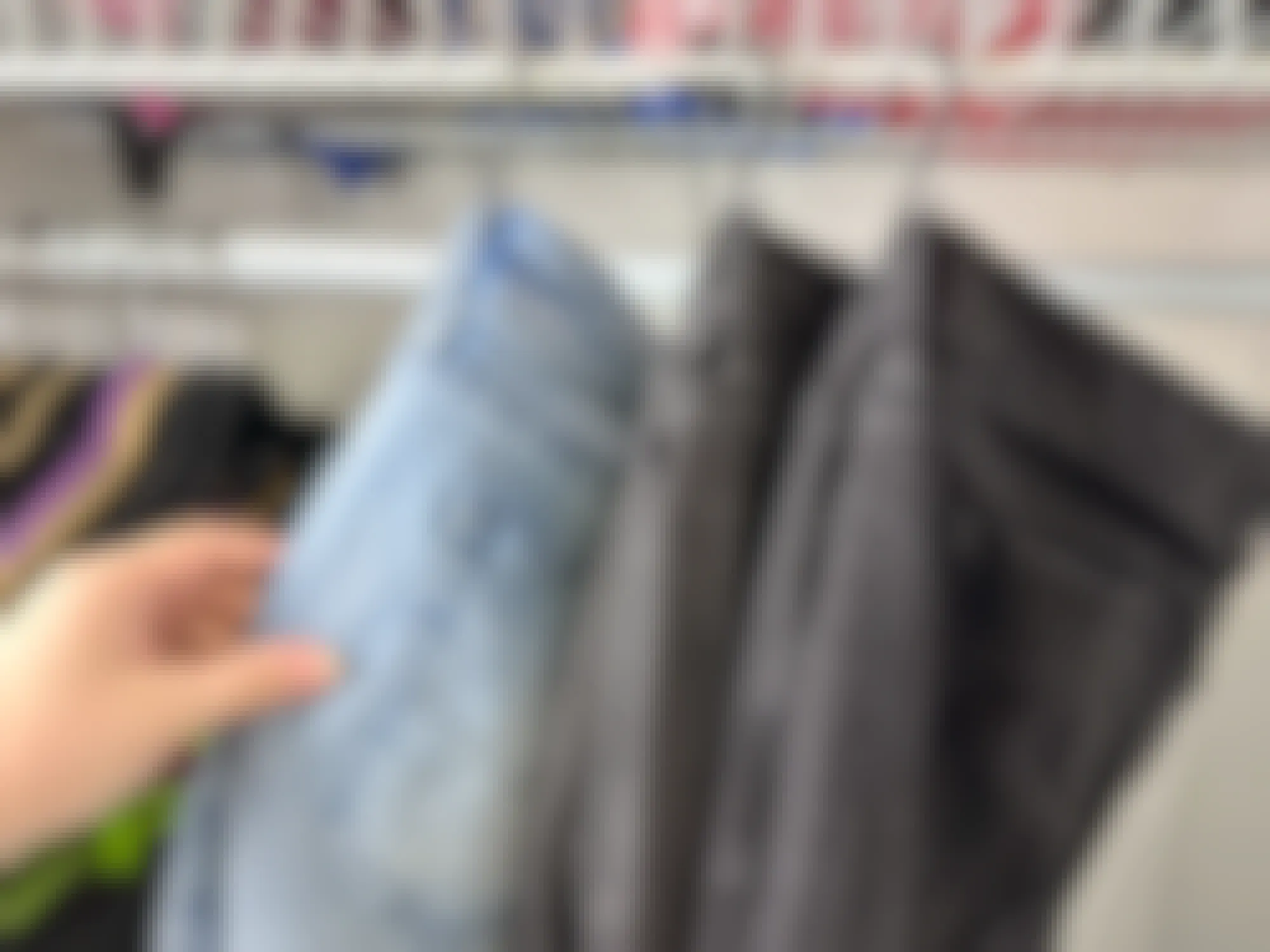 Someone hanging jeans on s hooks inside a closet