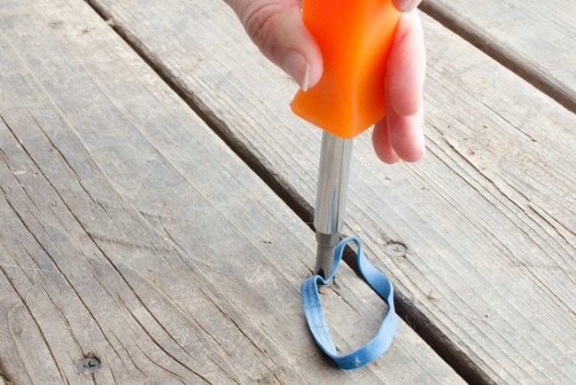 someone using screwdriver with rubber band to unscrew screw