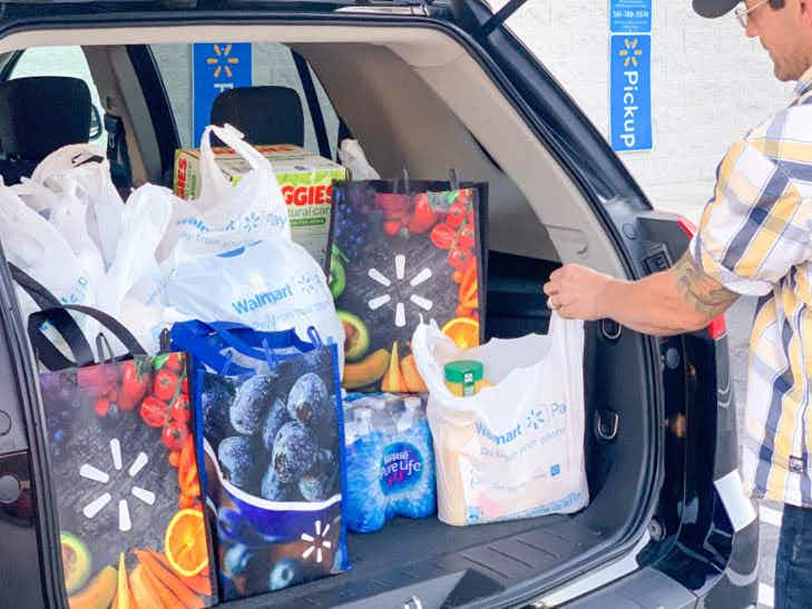 man loading walmart grocery pickup in back of car