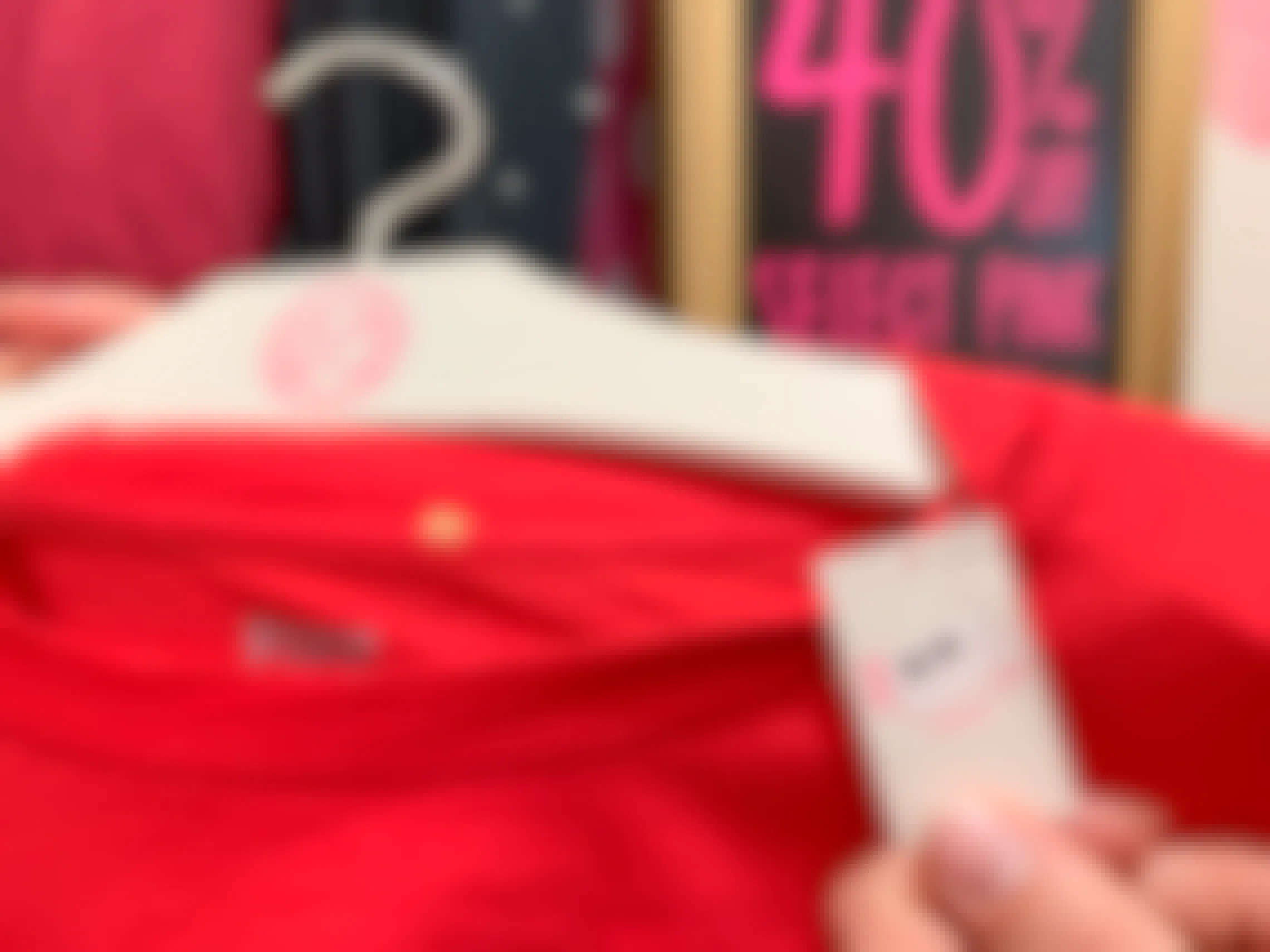A Pink clearance price tag on a red shirt with a 40% off Select Pink sign behind.
