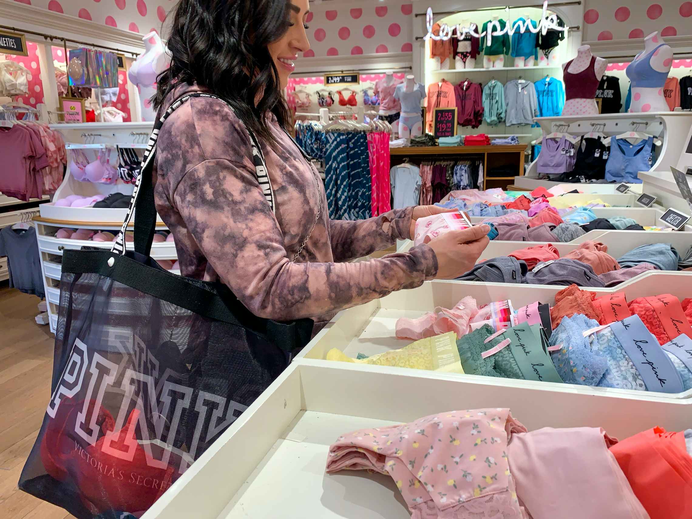 A woman holding Victoria's Secret underwear in hand at the store.