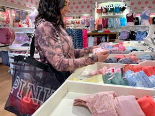 A woman holding Victoria's Secret underwear in hand at the store.