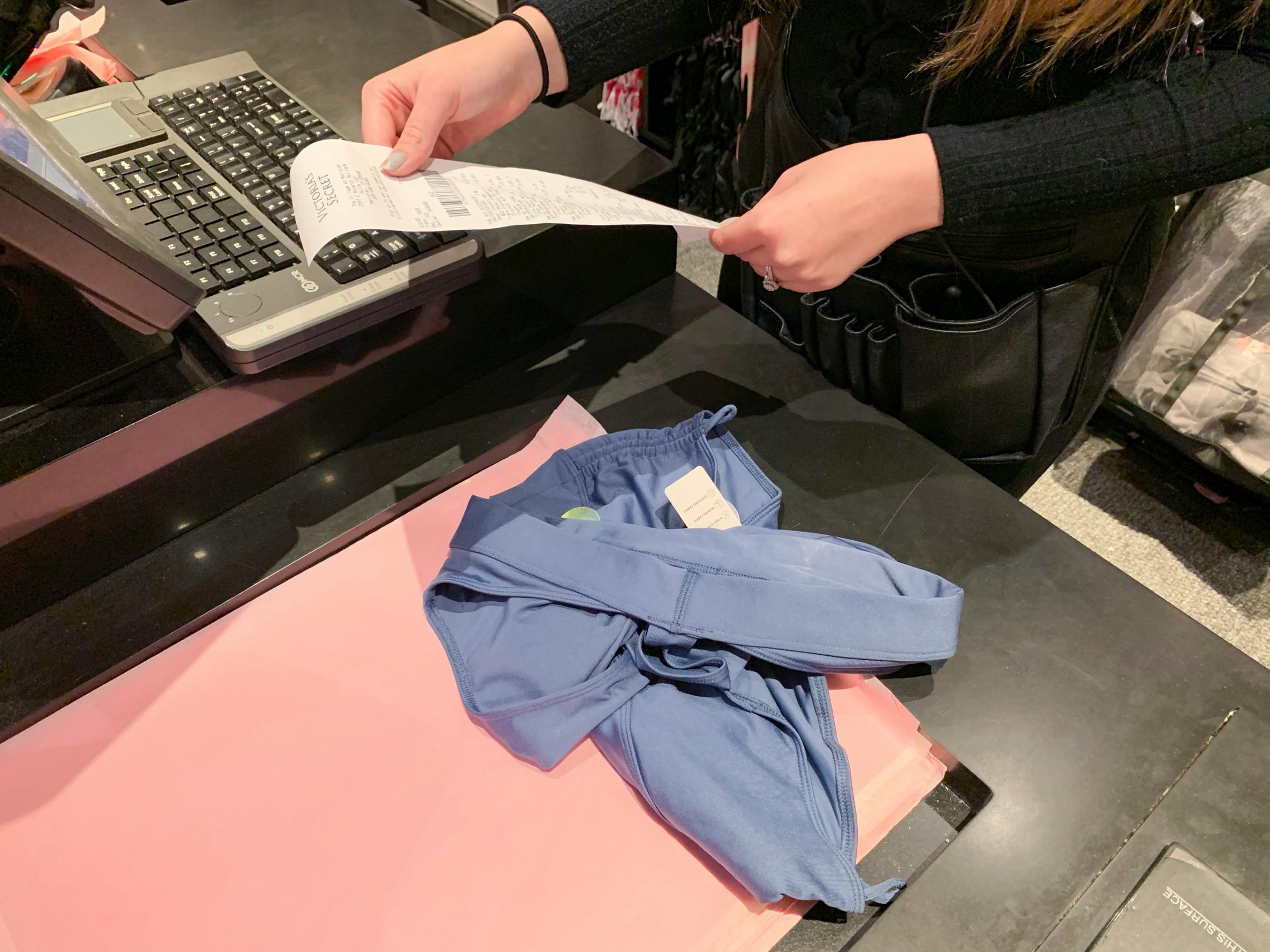 Female employee looking at a receipt to return an item at the register.