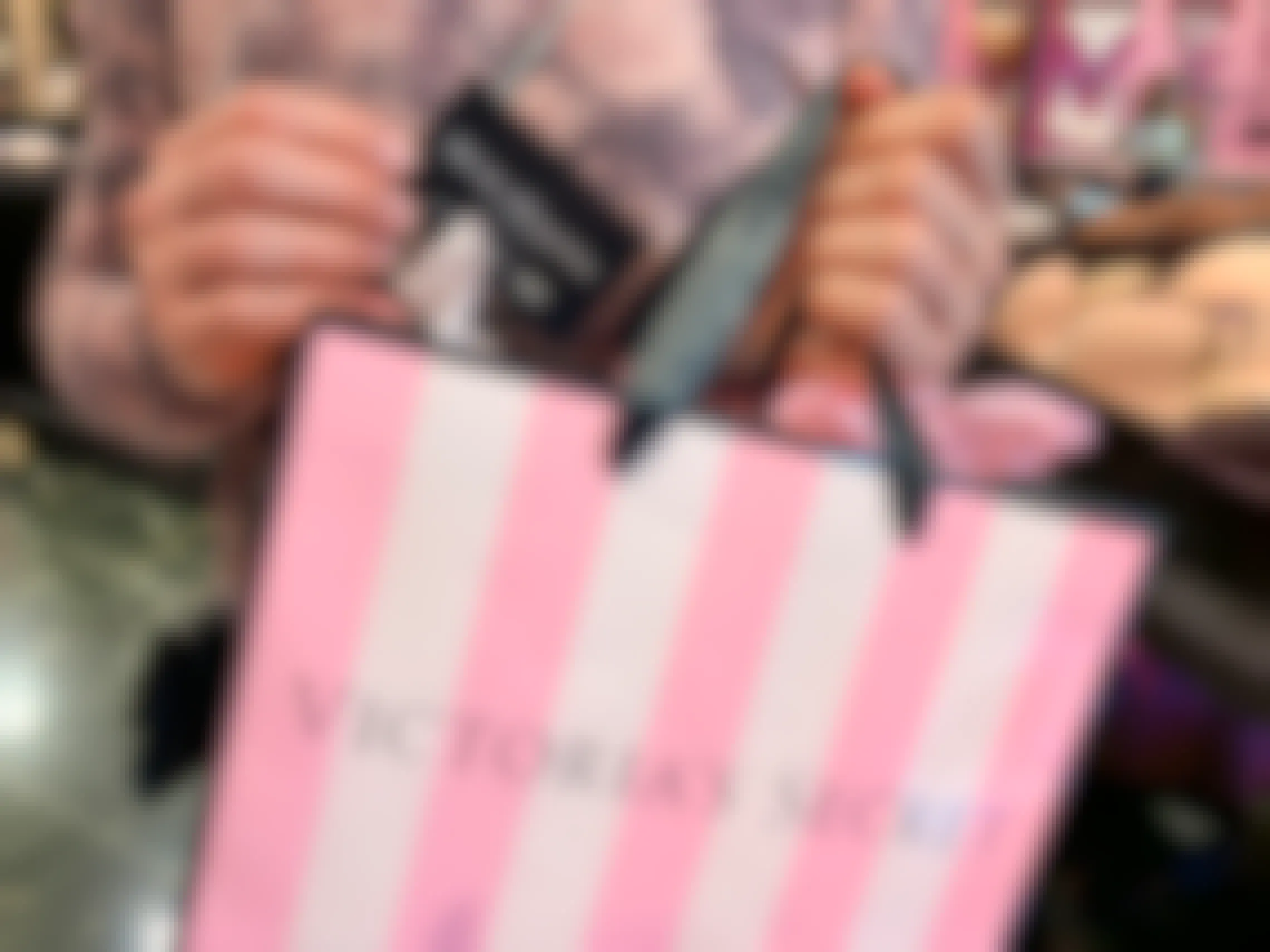 Woman holding shopping bag with Victoria's Secret reward card coupon for $20 off a $50 purchase.
