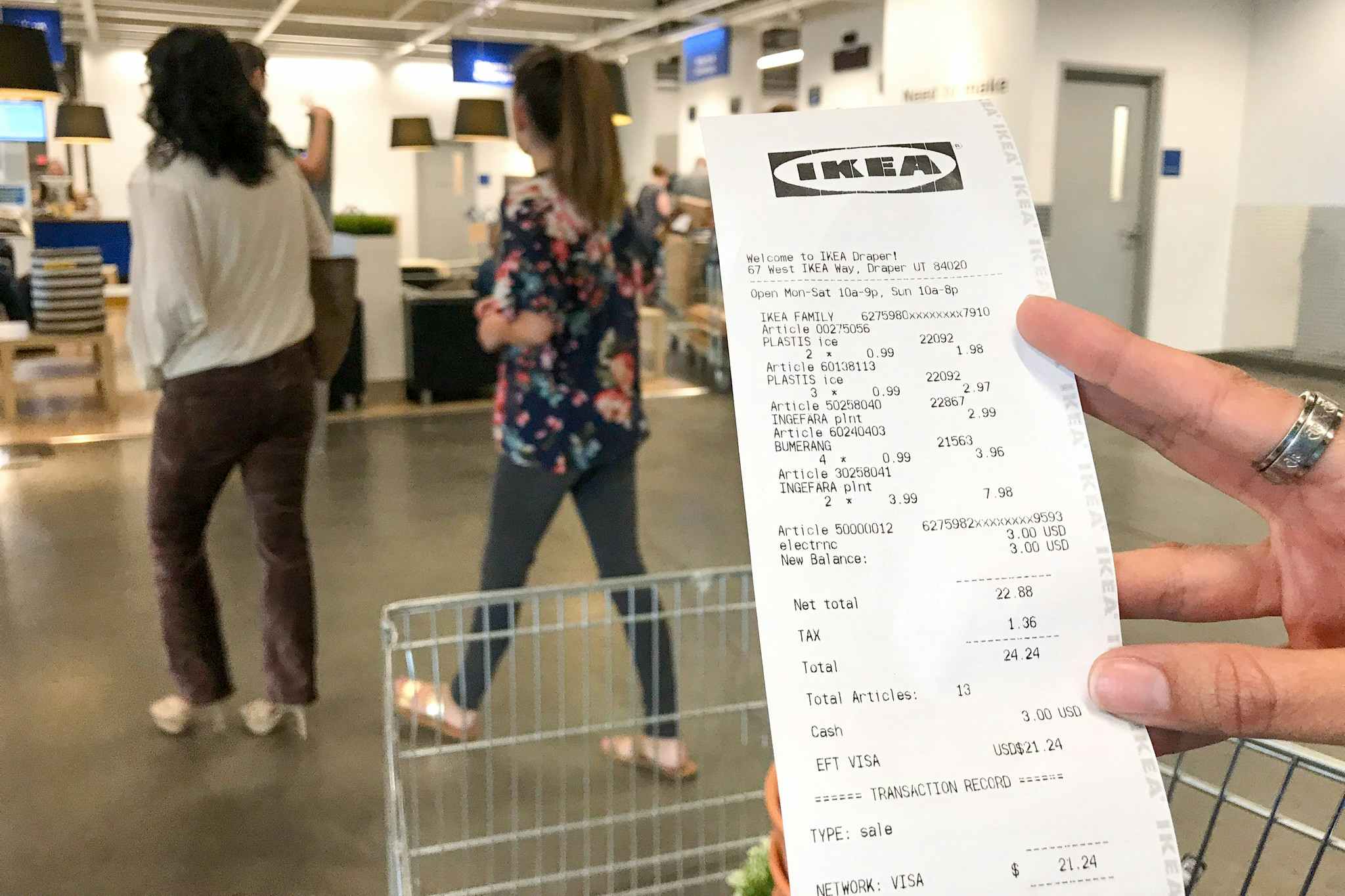 someone holding a costco receipt in front of a cart