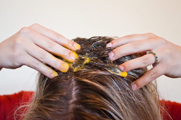 A person rubbing egg yolk into their hair.