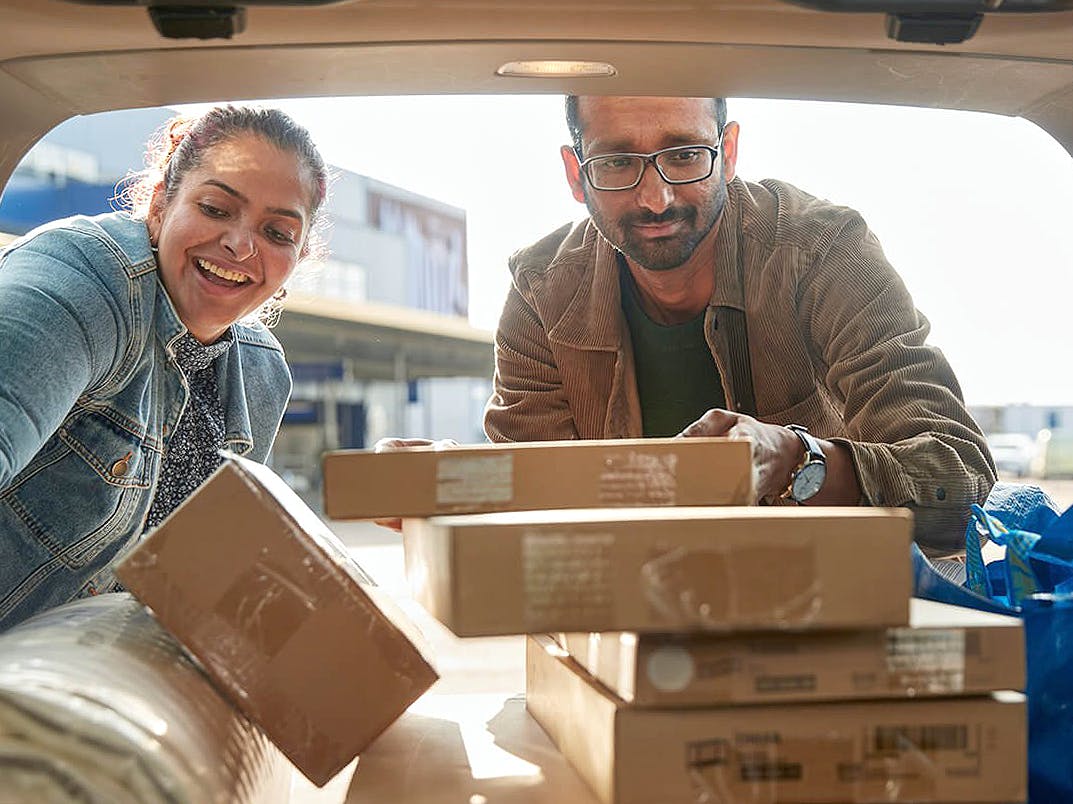 two people loading the trunk of their car with ikea boxes
