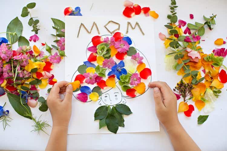 a child gluing flower petals to a paper to create art for mom