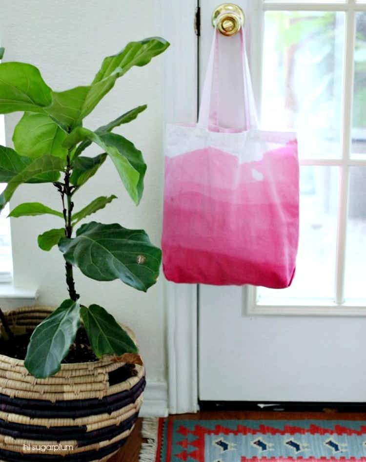 Canvas ombre-dyed bag hanging on a doorknob next to a fiddle leaf potted plant