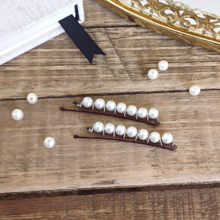 DIY pearl bobby pins sitting on a table with fake pearls nearby