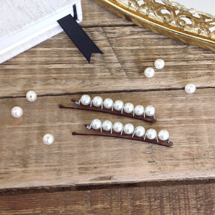 DIY pearl bobby pins sitting on a table with fake pearls nearby