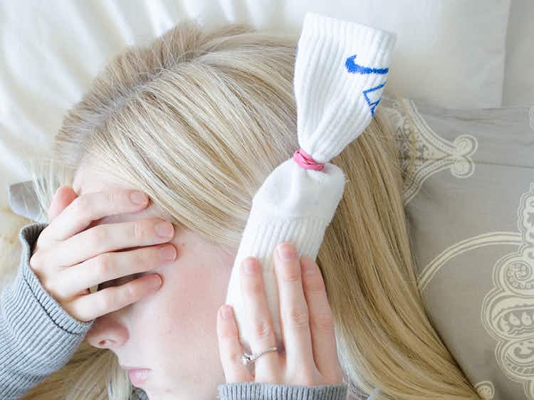 person holding sock filled with sea salt to painful ear
