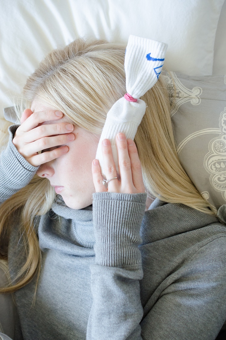 A person holding a sock up to their ear.
