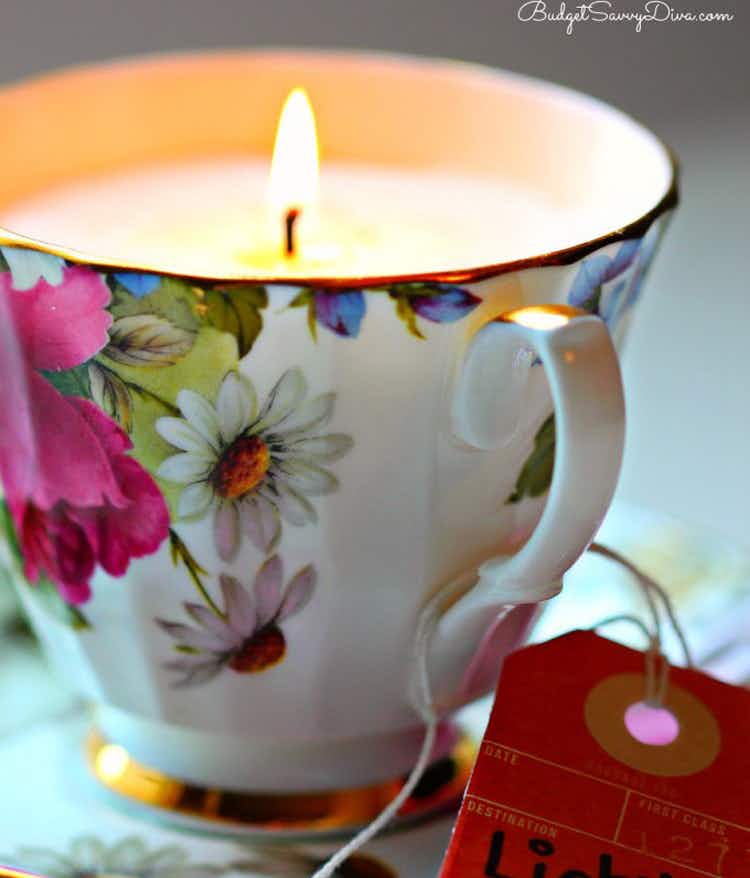 an antique teacup filled with candle wax and a lit candle