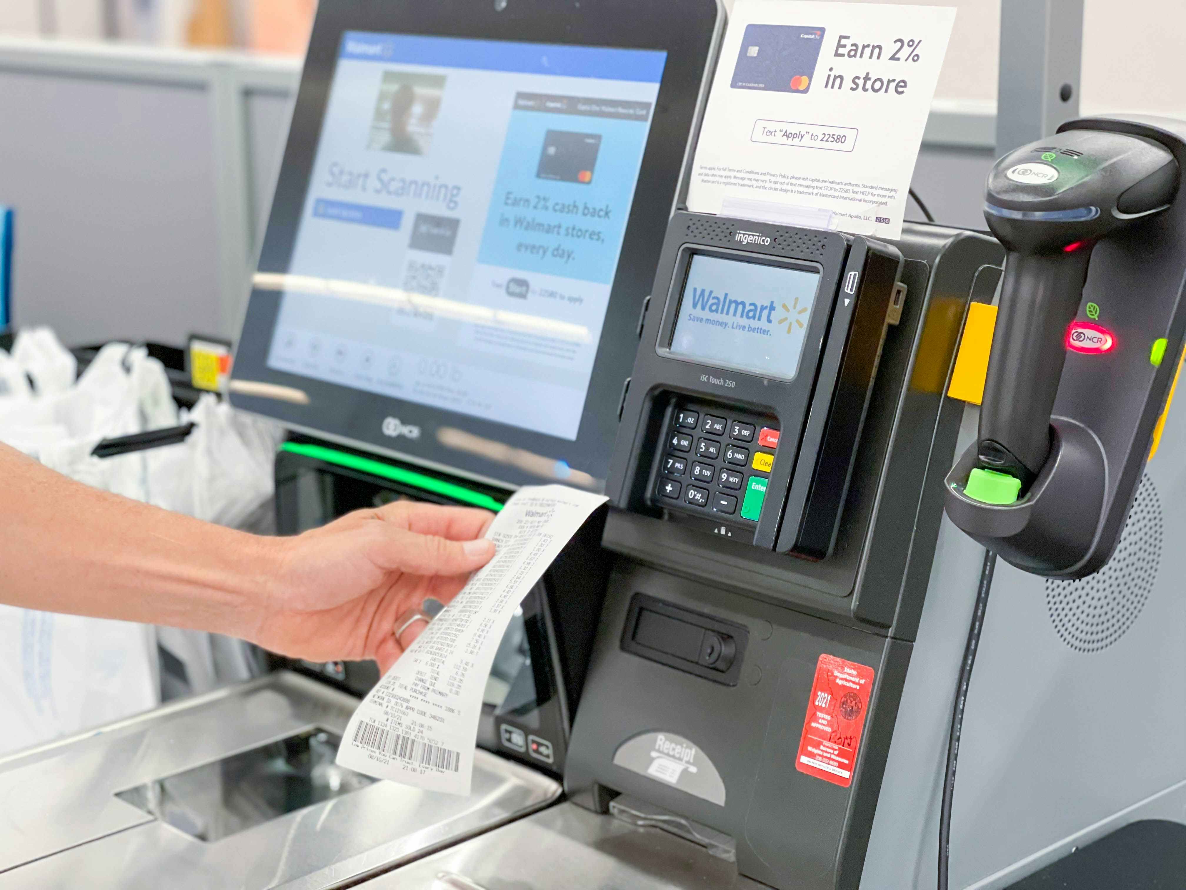 A person holding a receipt at a Walmart checkout stand