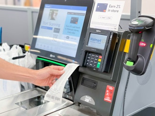 A person holding a receipt at a Walmart checkout stand