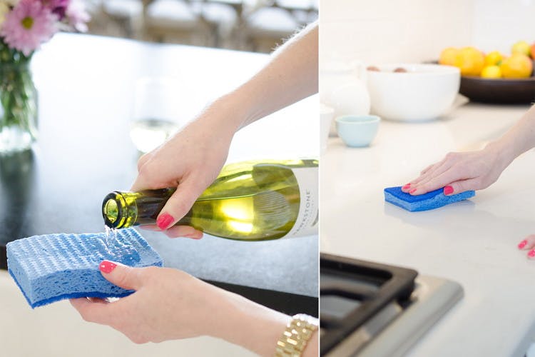 A person pouring wine onto a sponge next to a person wiping a counter with a sponge.