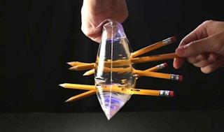 two hands sealing a Ziploc bag full of water and pushing sharp pencils through both sides.