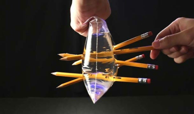 two hands sealing a Ziploc bag full of water and pushing sharp pencils through both sides.