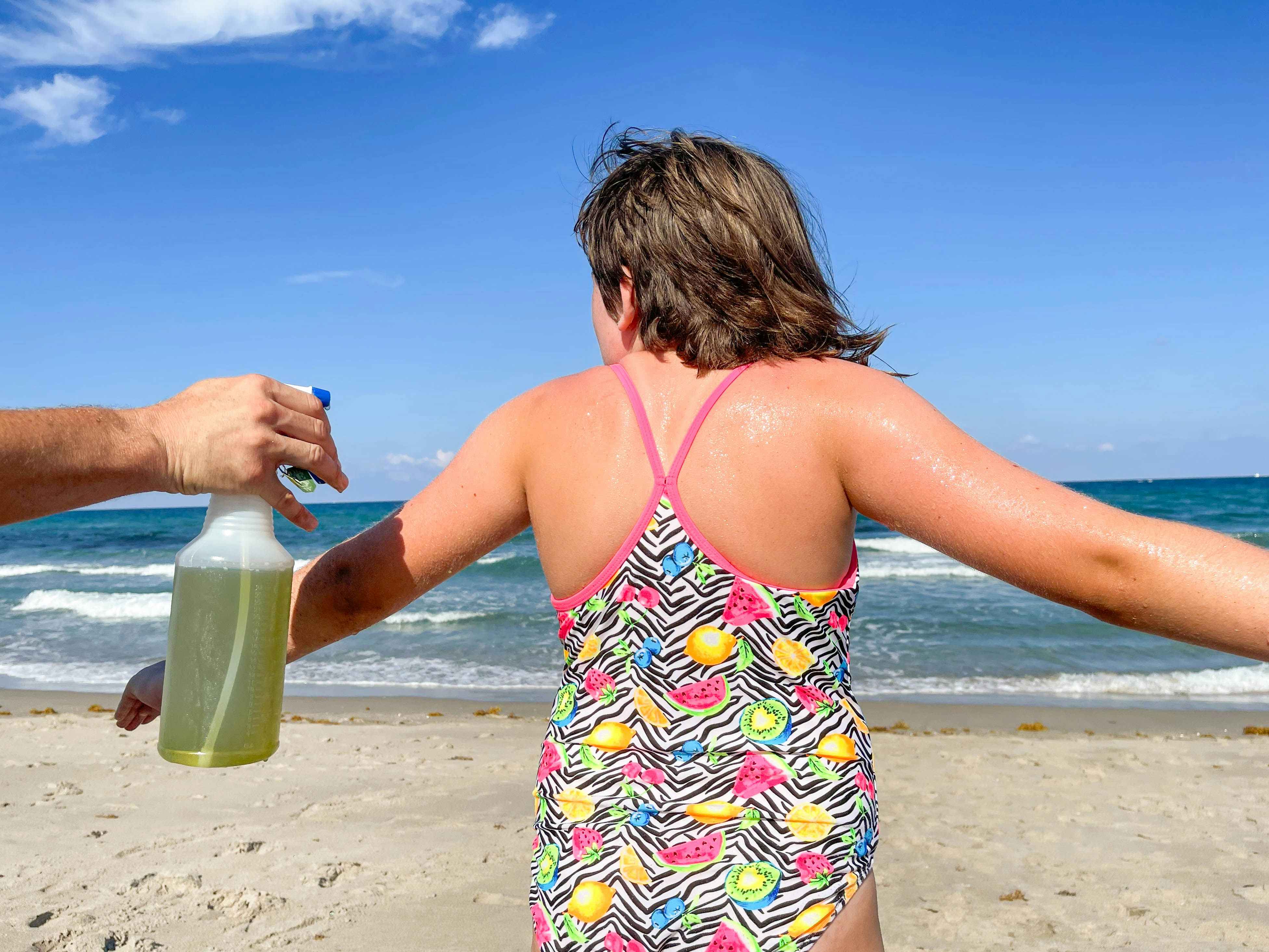 someone spraying green tea on a girl at the beach
